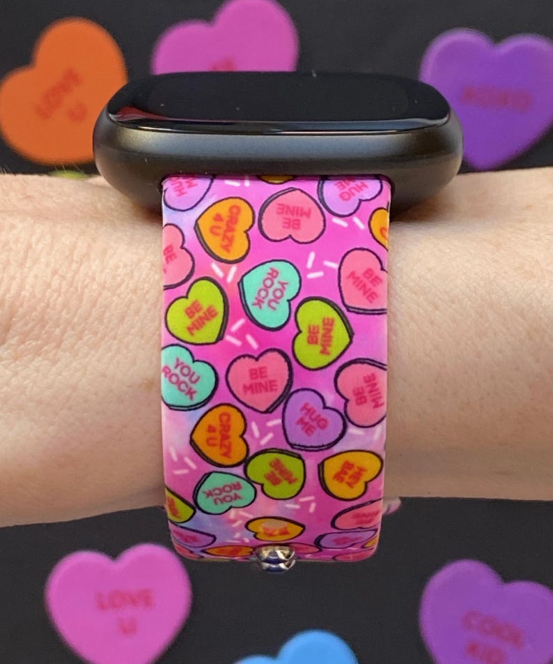 May include: Pink and white watch band with a pattern of candy hearts that say "Be Mine", "You Rock", "Hug Me", and "Crazy 4 U".