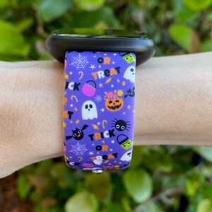 Puede incluir: Pulsera de reloj de silicona morada con un estampado de tem&aacute;tica de Halloween que presenta fantasmas, murci&eacute;lagos, ara&ntilde;as, calabazas, ma&iacute;z dulce y el texto "Trick or Treat".