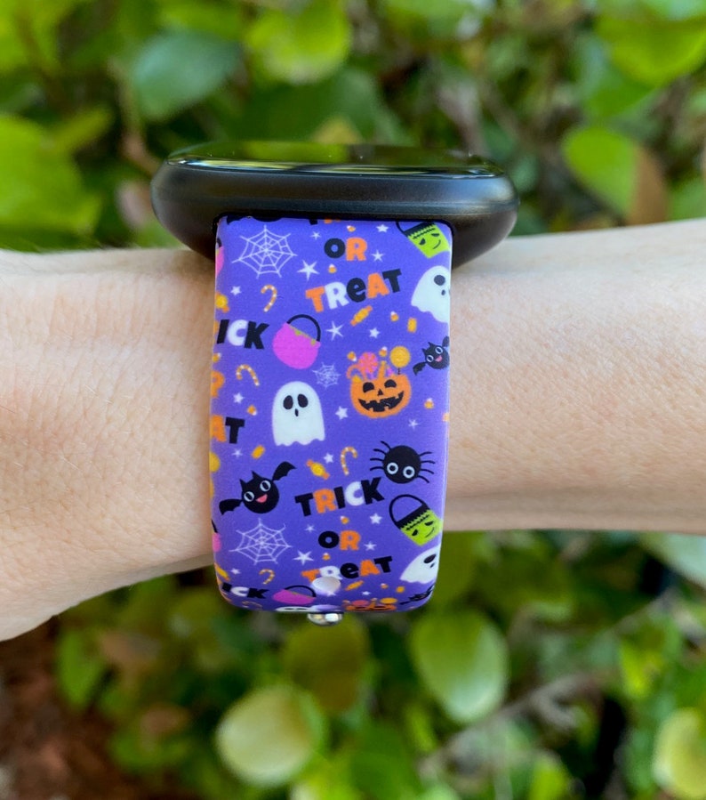 Puede incluir: Pulsera de reloj de silicona morada con un estampado de tem&aacute;tica de Halloween que presenta fantasmas, murci&eacute;lagos, ara&ntilde;as, calabazas, ma&iacute;z dulce y el texto "Trick or Treat".