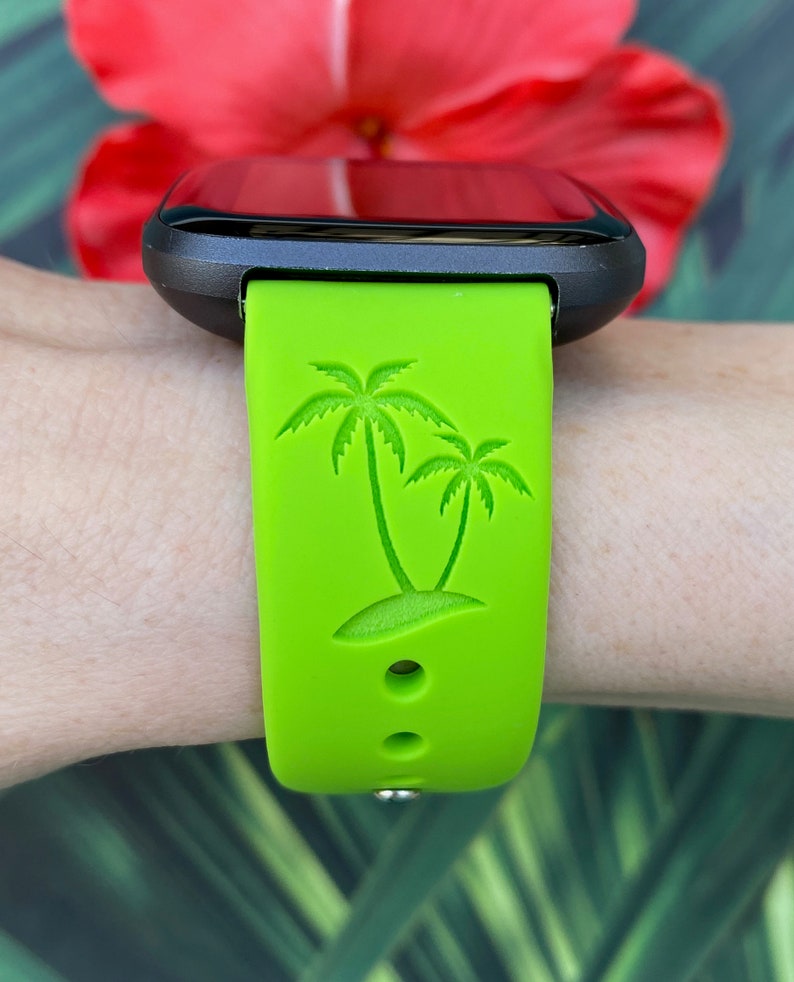 May include: A green silicone watch band with a palm tree design. The band is compatible with smartwatches.