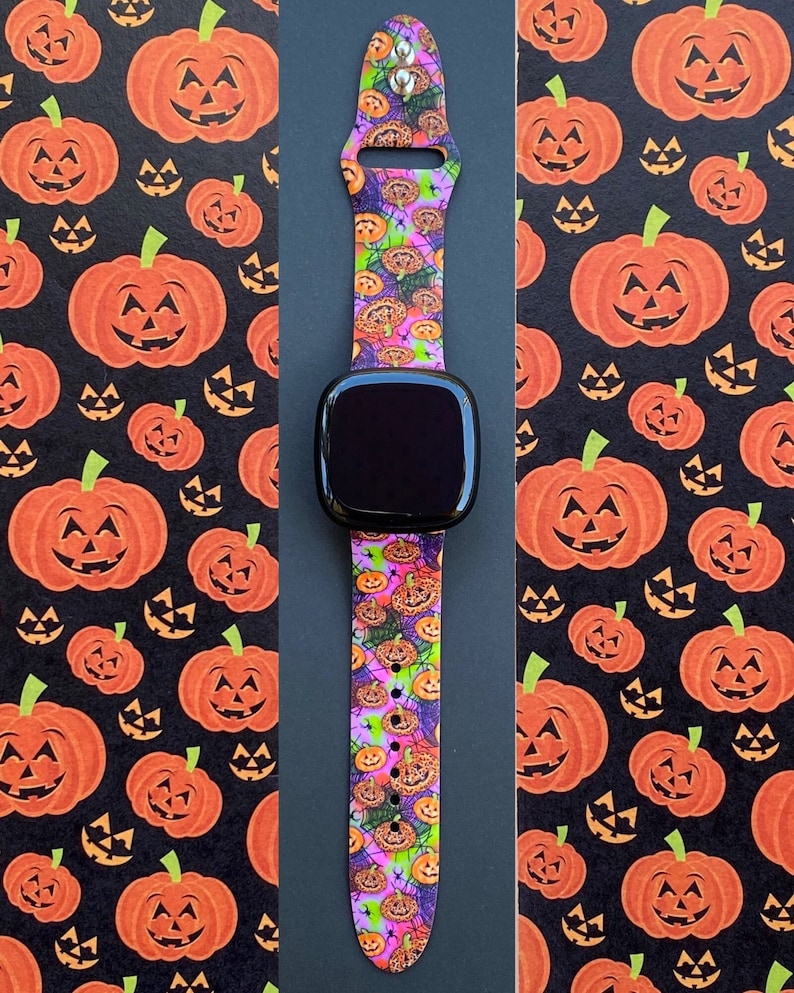 May include: A black smartwatch with a bright pink, orange, and green patterned band featuring a repeating pattern of jack-o'-lanterns. The band is made of silicone and has a buckle closure.