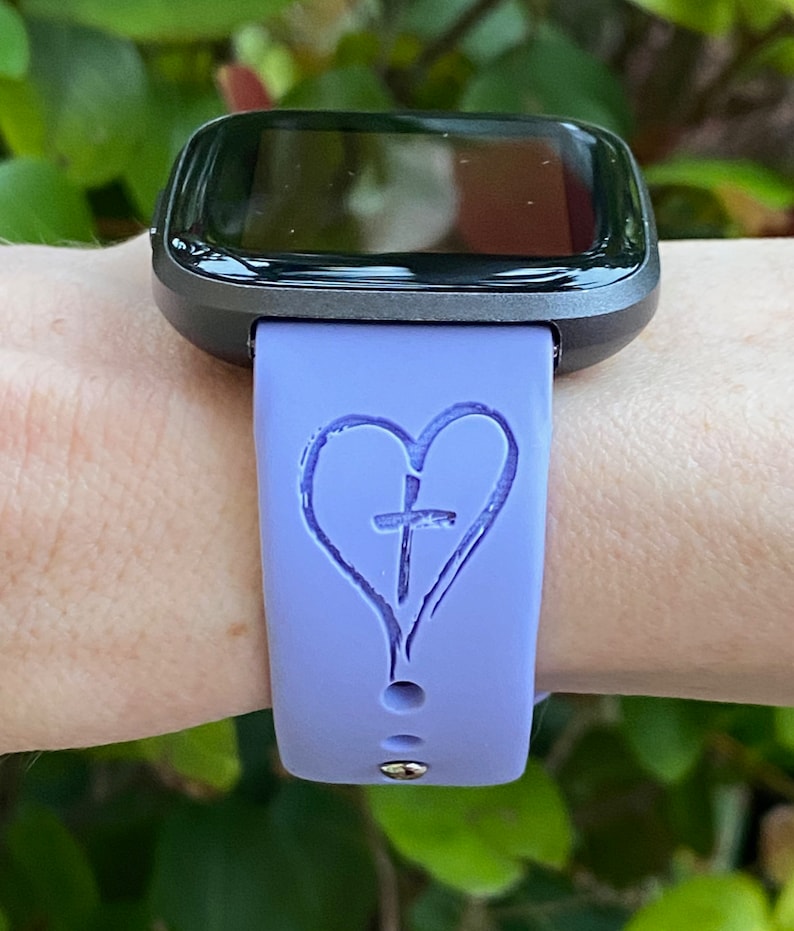 May include: A purple silicone watch band with a heart and cross design.