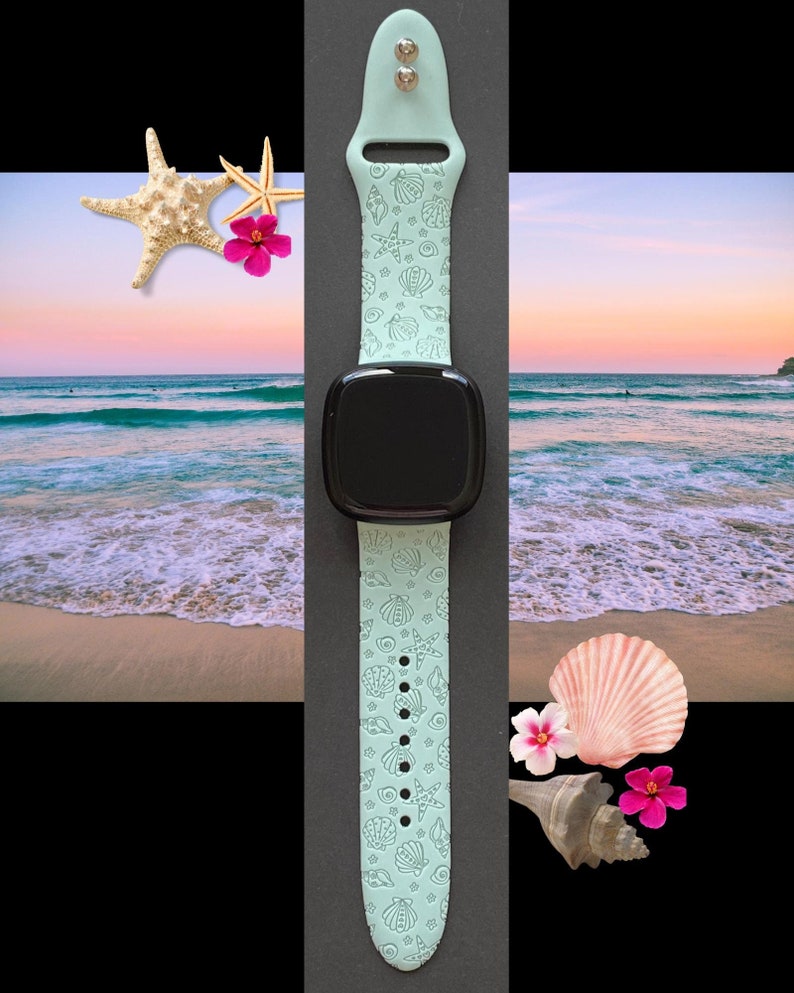 May include: A light blue Apple Watch band with a seashell pattern. The band is shown on a black background with a beach scene in the background.