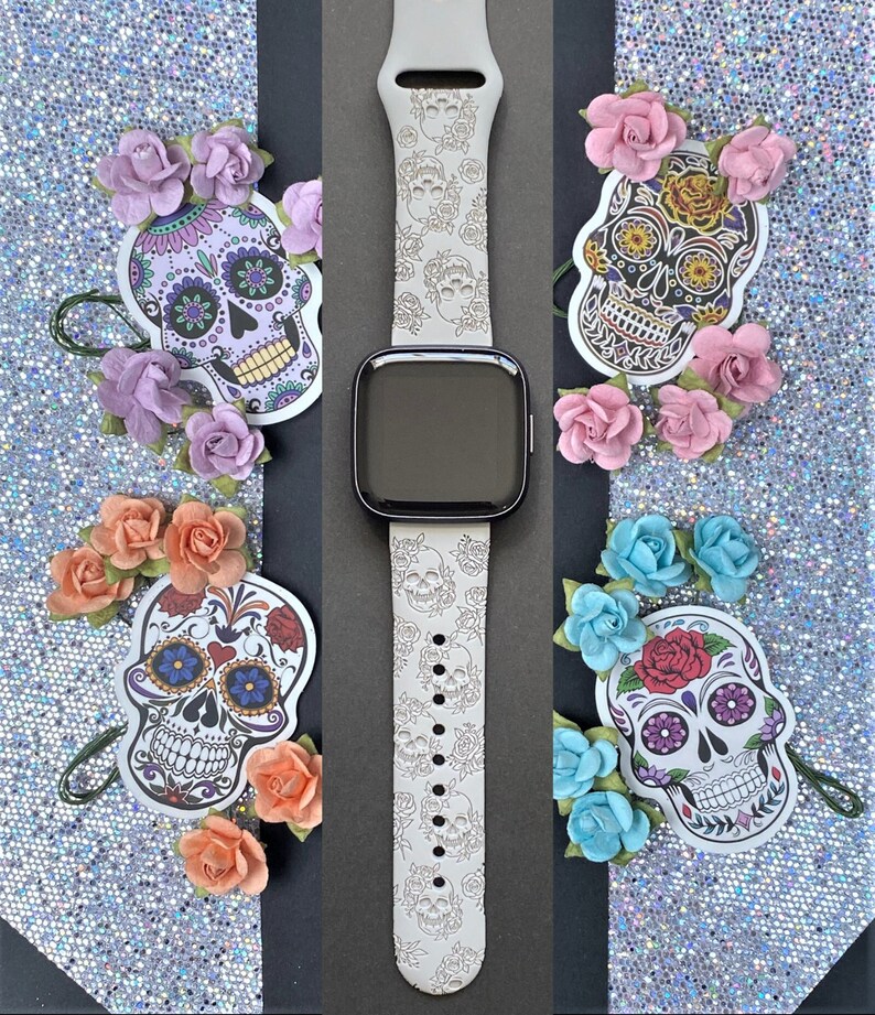 K&ouml;nnte beinhalten: Wei&szlig;es Silikon-Armband mit einem Muster aus Zucker Totenk&ouml;pfen und Blumen. Das Armband ist kompatibel mit Apple Watch.
