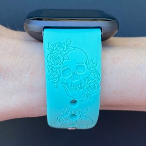 Op de afbeelding: Een turquoise blauwe siliconen horlogeband met een schedel- en rozenontwerp. De band is ontworpen voor een smartwatch.