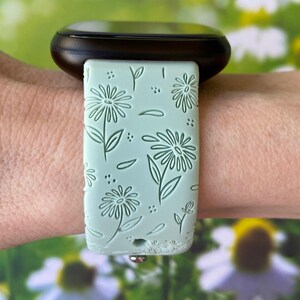 May include: A light green watch band with a floral pattern. The band is made of silicone and has a smooth finish.