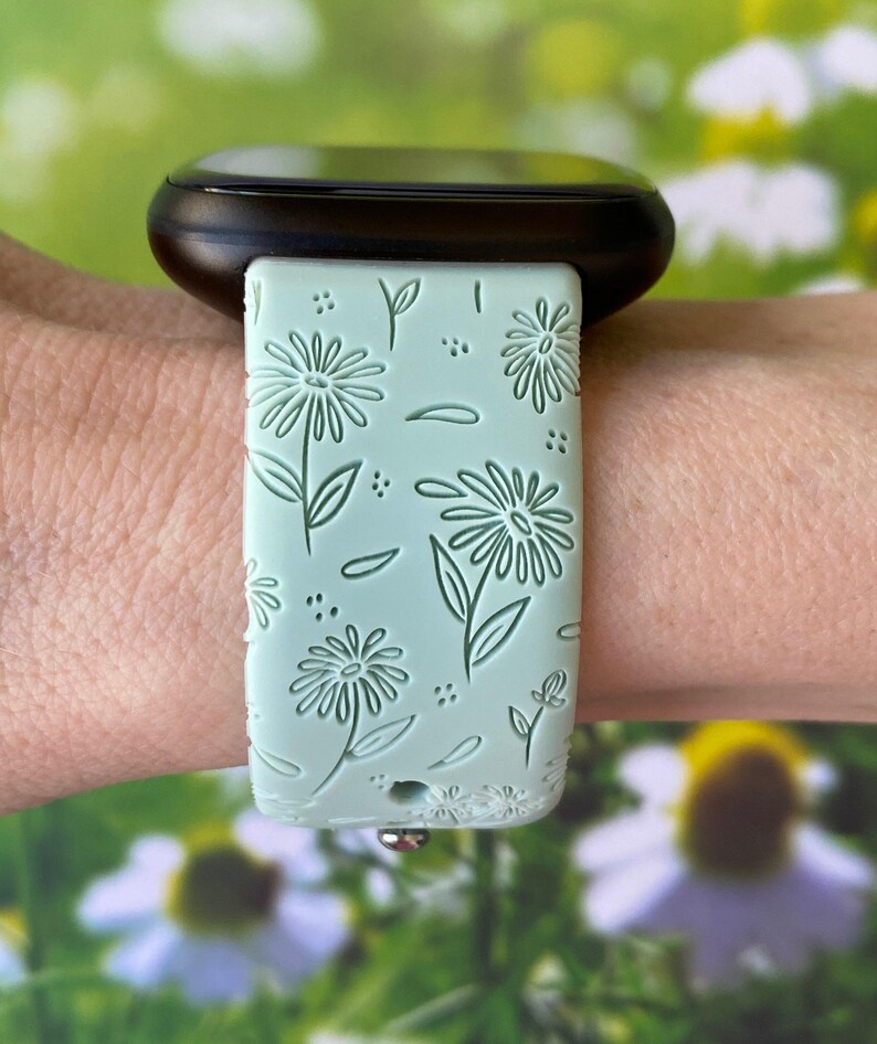 May include: A light green watch band with a floral pattern. The band is made of silicone and has a smooth finish.