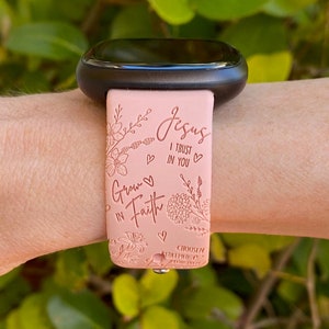 May include: A pink silicone watch band with a floral design and the text "Jesus I trust in you" and "Grow in Faith". The band also has the text "Chosen Redeemed Forever".