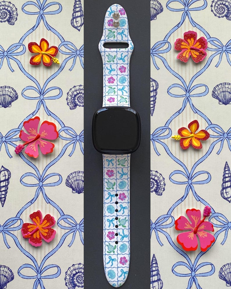 Op de afbeelding: Witte smartwatchband met een tropisch patroon van schildpadden, bloemen en schelpen. De band staat tegen een achtergrond met een herhalend patroon van blauwe strikken en schelpen, en is omgeven door kleurrijke bloemdecoraties.