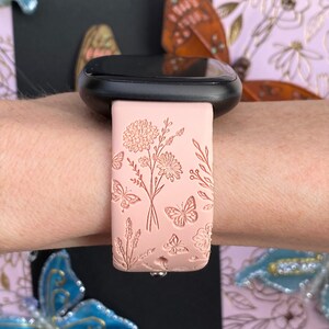 May include: A pink silicone watch band with a floral and butterfly design. The band is embossed with delicate flowers and butterflies.