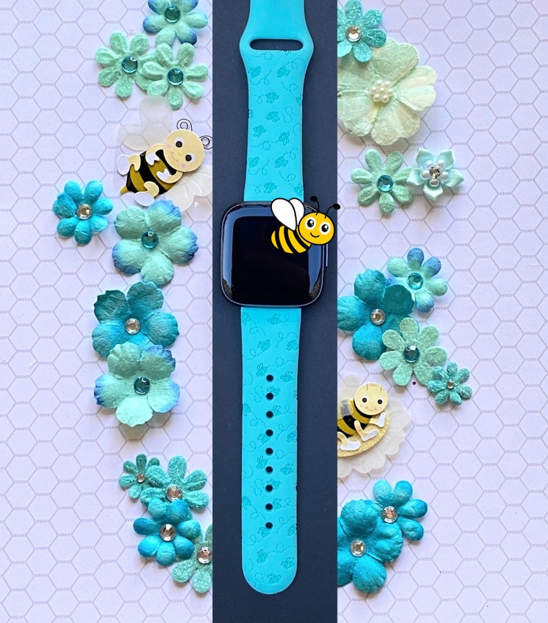 May include: A turquoise blue silicone watch band with a repeating pattern of bees and honeycombs. The band is designed for a smartwatch and has a black watch face with a cartoon bee on it.