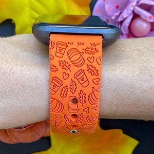 May include: Orange silicone watch band with a fall-themed design featuring coffee cups, pumpkins, leaves, and hearts.