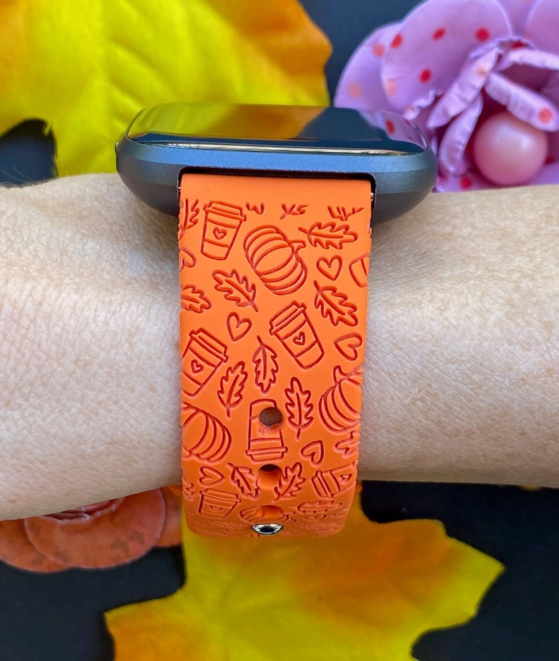 May include: Orange silicone watch band with a fall-themed design featuring coffee cups, pumpkins, leaves, and hearts.