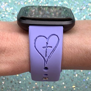 May include: A purple silicone watch band with a heart and cross design. The band is designed for a smartwatch.