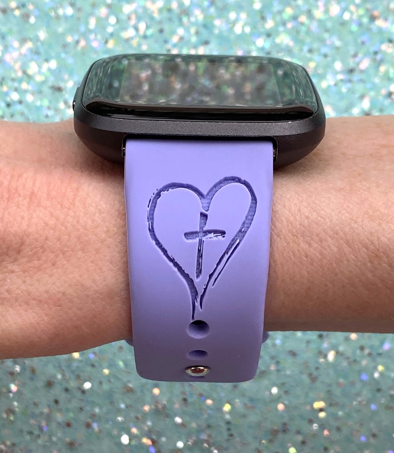 May include: A purple silicone watch band with a heart and cross design. The band is designed for a smartwatch.