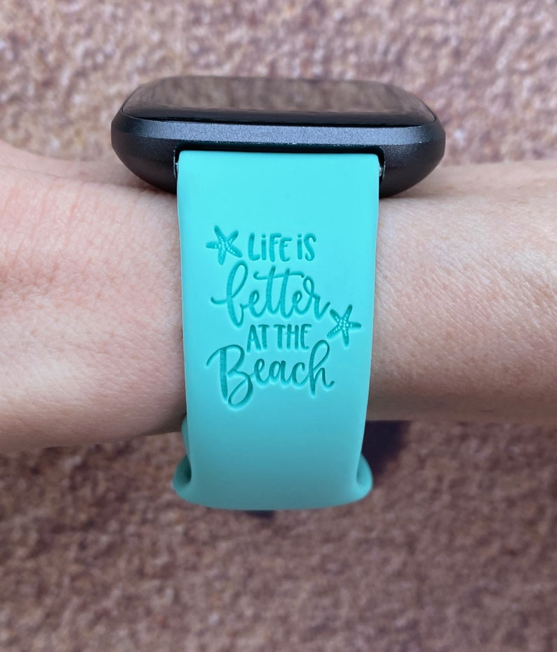 May include: A turquoise blue silicone watch band with the text "Life is better at the beach" and a starfish graphic.