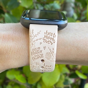 May include: A beige smartwatch band with a floral design and the text "best mom ever", "first my mother forever my friend", and "love you".