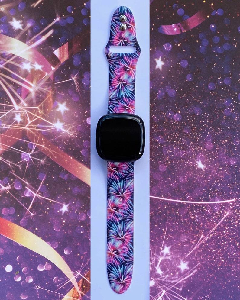 May include: A black smartwatch with a colorful firework print band. The band is made of silicone and has a secure clasp.
