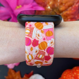 May include: A pink and orange patterned Apple Watch band with a design of pumpkins, coffee cups, and flowers.