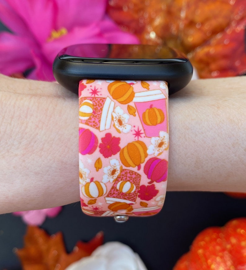 May include: A pink and orange patterned Apple Watch band with a design of pumpkins, coffee cups, and flowers.