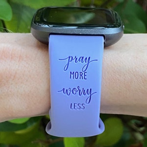 May include: A purple silicone watch band with the text "pray more worry less" printed on it.
