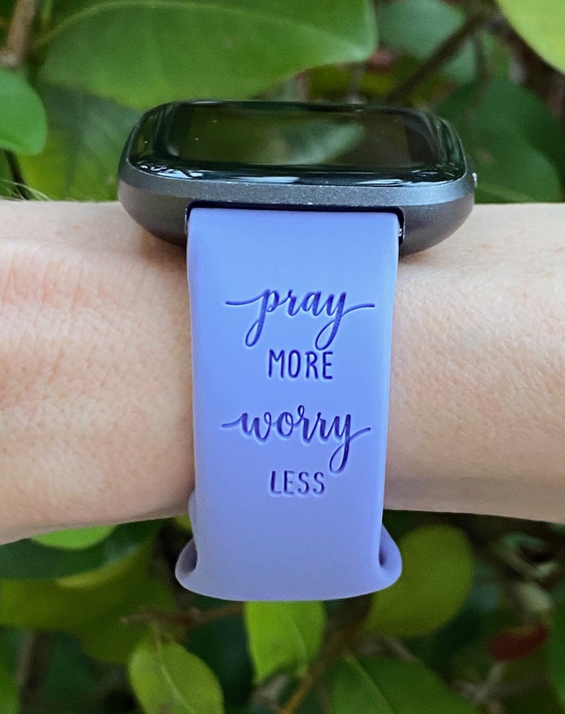 May include: A purple silicone watch band with the text "pray more worry less" printed on it.