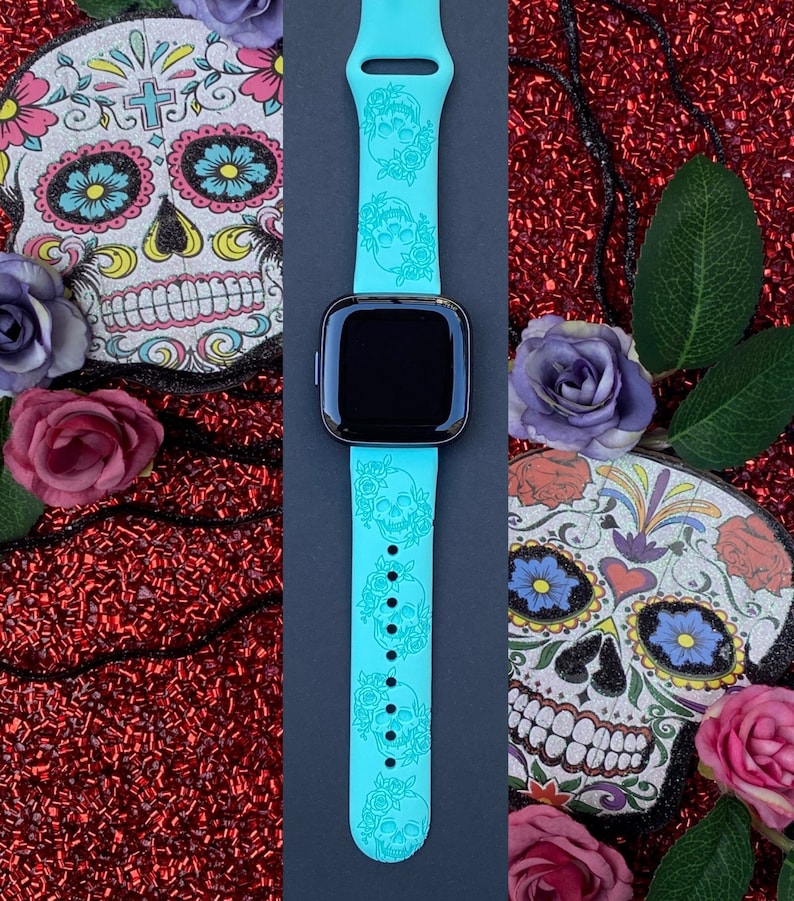 Op de afbeelding: Een turquoise blauwe siliconen horlogeband met een herhalend patroon van witte suiker schedels en bloemen. De band is ontworpen voor een smartwatch.