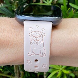 May include: A pink silicone watch band with a white pug design and three hearts. The band has a silver buckle and is compatible with a smartwatch.