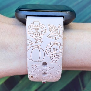 May include: A pink silicone watch band with a Thanksgiving theme. The band features a repeating pattern of turkeys, pumpkins, and leaves.