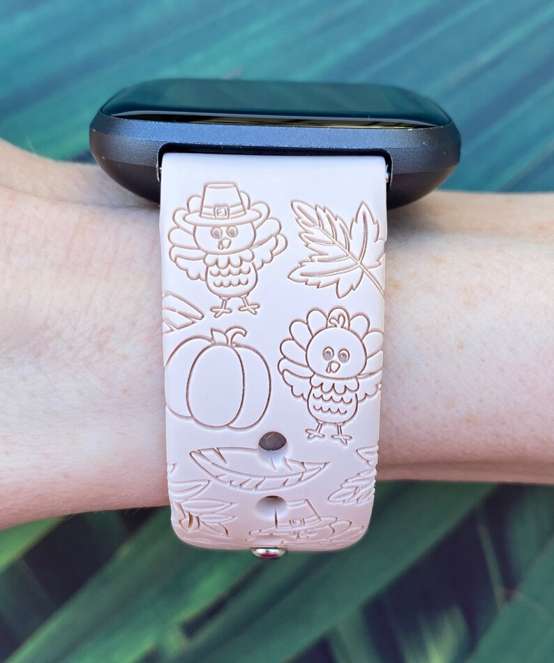 May include: A pink silicone watch band with a Thanksgiving theme. The band features a repeating pattern of turkeys, pumpkins, and leaves.