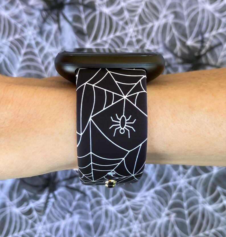 May include: Black and white watch band with a spider web and spider design.