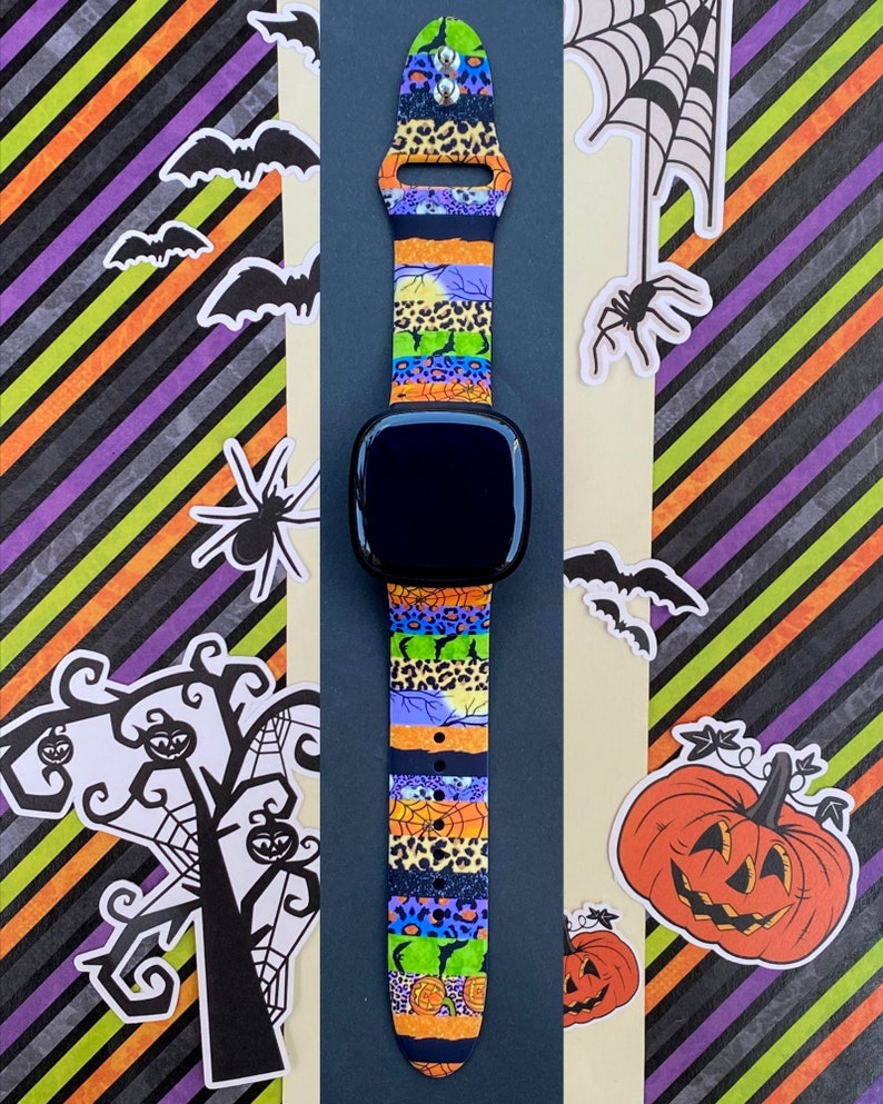 May include: A colorful Halloween-themed watch band with a variety of patterns, including leopard print, spiderwebs, and pumpkins. The band is made of silicone and is compatible with most smartwatches.