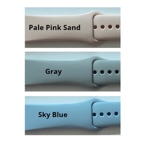 May include: Three different colored watch bands. The bands are made of a soft, flexible material. The colors are pale pink sand, gray, and sky blue.