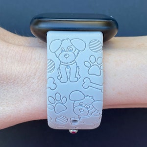 Puede incluir: Una correa de reloj de silicona gris con un patr&oacute;n de perro y hueso blanco. La correa est&aacute; dise&ntilde;ada para un reloj inteligente.