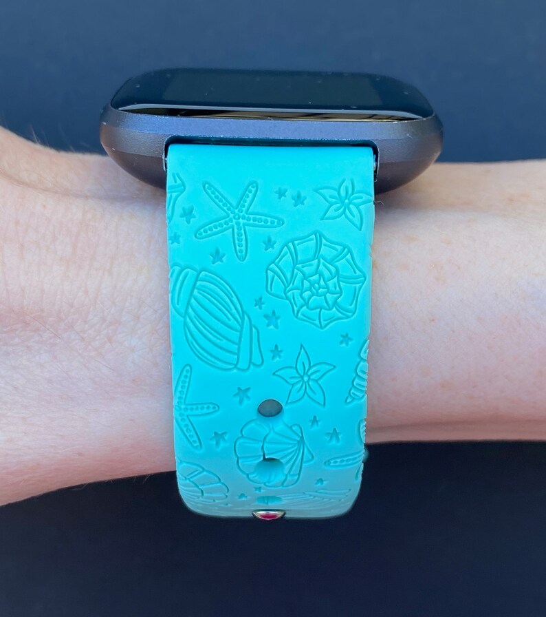 May include: A turquoise blue silicone watch band with a seashell and starfish pattern. The band is designed for a smartwatch.
