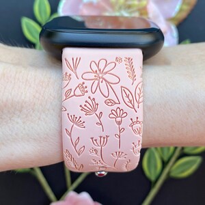 May include: A pink silicone watch band with a floral design. The band is embossed with delicate flowers and leaves.