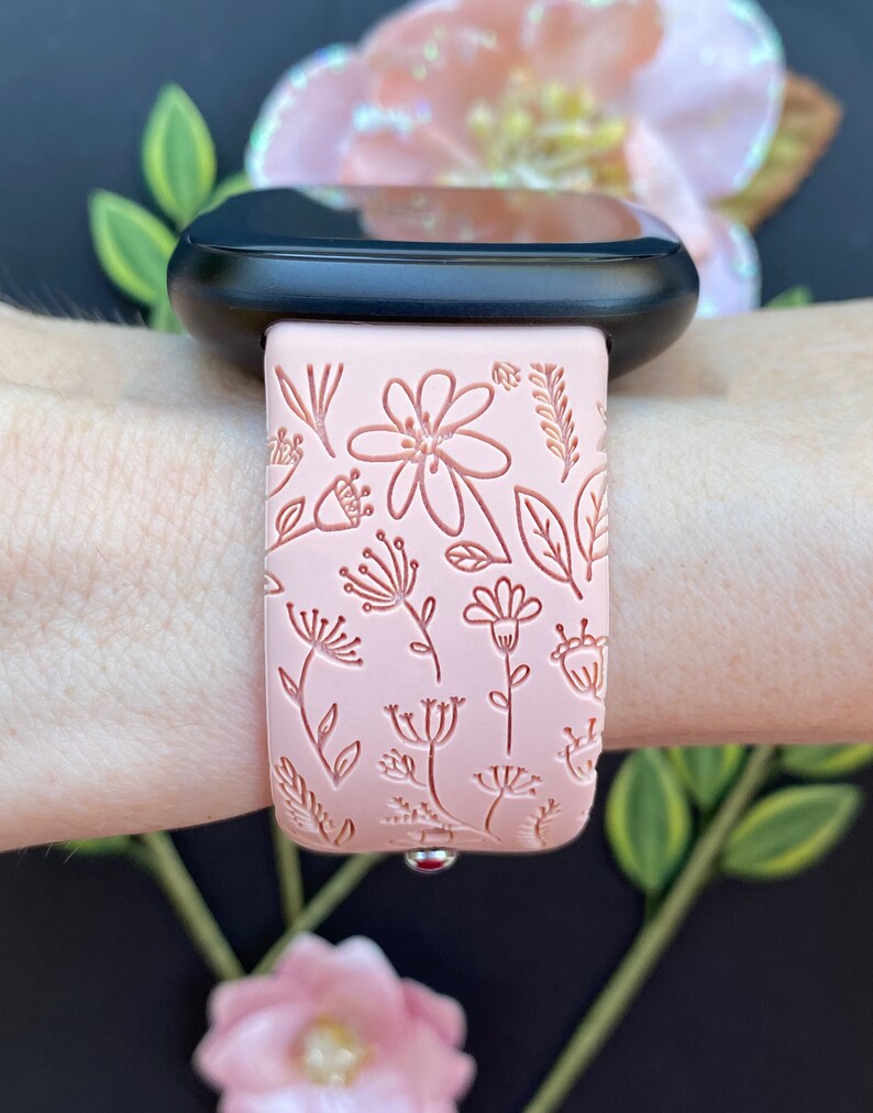 May include: A pink silicone watch band with a floral design. The band is embossed with delicate flowers and leaves.