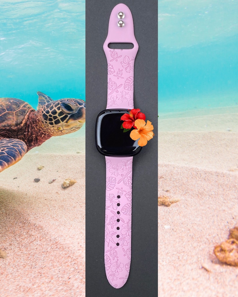 May include: A pink silicone watch strap with a floral design. The strap has a black watch face and is decorated with pink and orange flowers.