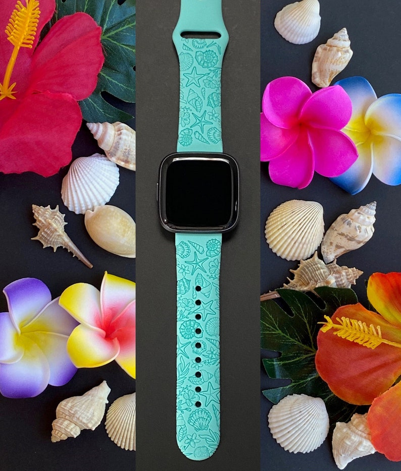 May include: A turquoise blue Apple Watch band with a seashell and floral design. The band is shown against a background of seashells and tropical flowers.