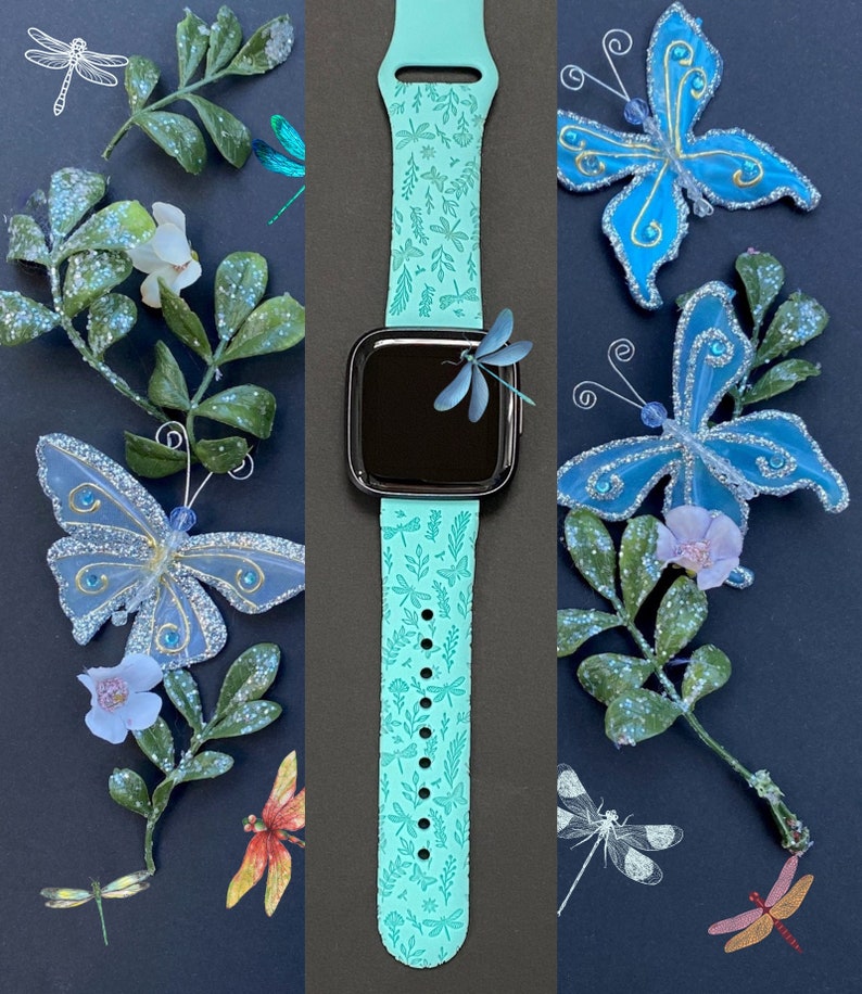 K&ouml;nnte beinhalten: Ein t&uuml;rkisfarbenes Silikon-Armband mit einem Libellen- und Blattmotiv. Das Armband ist auf einem schwarzen Hintergrund mit blauen Schmetterlingen und gr&uuml;nen Bl&auml;ttern abgebildet.
