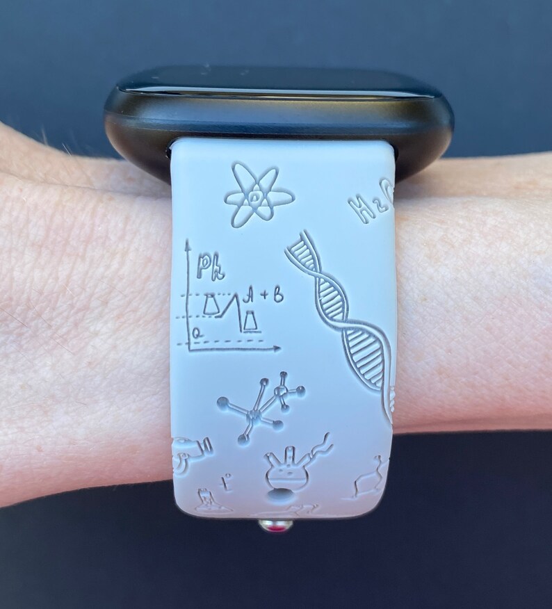 Pu&ograve; includere: Un cinturino per orologio in silicone bianco con un quadrante nero. Il cinturino ha un tema scientifico con disegni di una catena di DNA, un atomo, una beuta e un grafico. Il testo "H2O" &egrave; visibile sul cinturino.