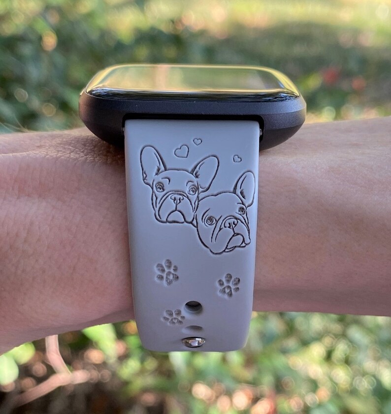 May include: A gray silicone watch band with a black watch face. The band features two French bulldog faces and paw prints.