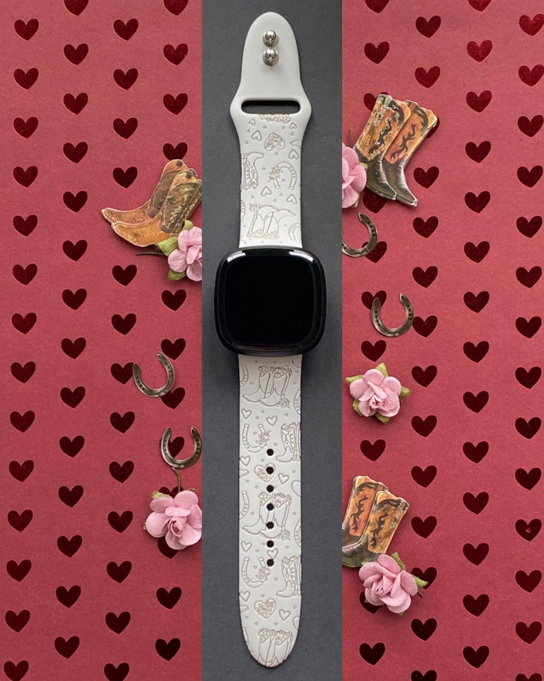 May include: White Apple Watch band with a white background and a pattern of cowboy boots and horseshoes. The band is on a red background with hearts.