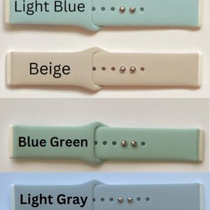 May include: Four silicone watch bands in different colors: light blue, beige, blue green, and light gray. Each band has a white edge and silver metal clasps.