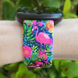 May include: A black smartwatch with a pink flamingo and tropical floral print silicone strap.
