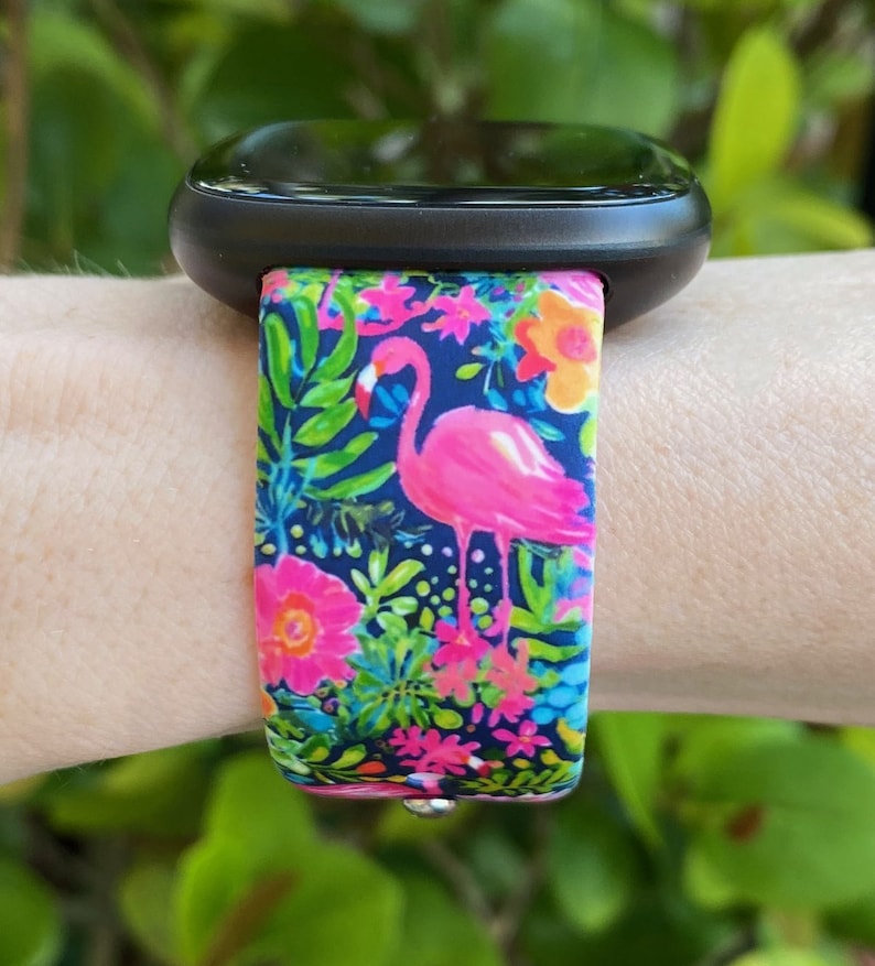 May include: A black smartwatch with a pink flamingo and tropical floral print silicone strap.