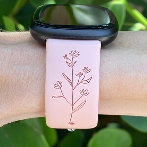 May include: A pink silicone watch band with a delicate floral design. The band is compatible with smartwatches.