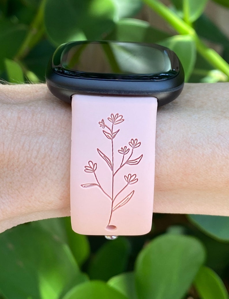 May include: A pink silicone watch band with a delicate floral design. The band is compatible with smartwatches.