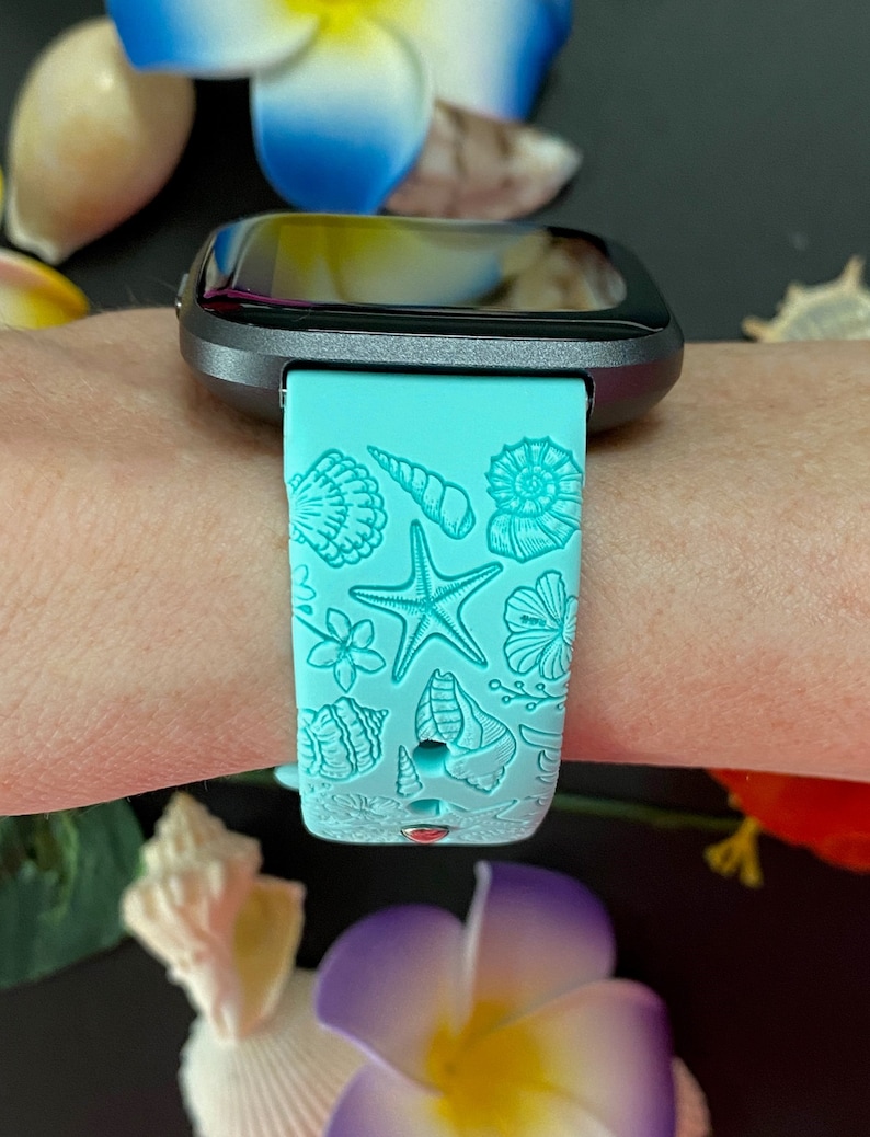 May include: A turquoise blue watch band with a seashell and starfish design. The band is made of silicone and has a black watch face.