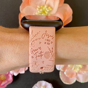 May include: A pink silicone watch band with a floral design and the text "Grow in Faith" and "Jesus I Trust in You".